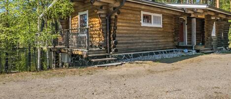 A rustic log cabin with a porch, a small window, and a door.