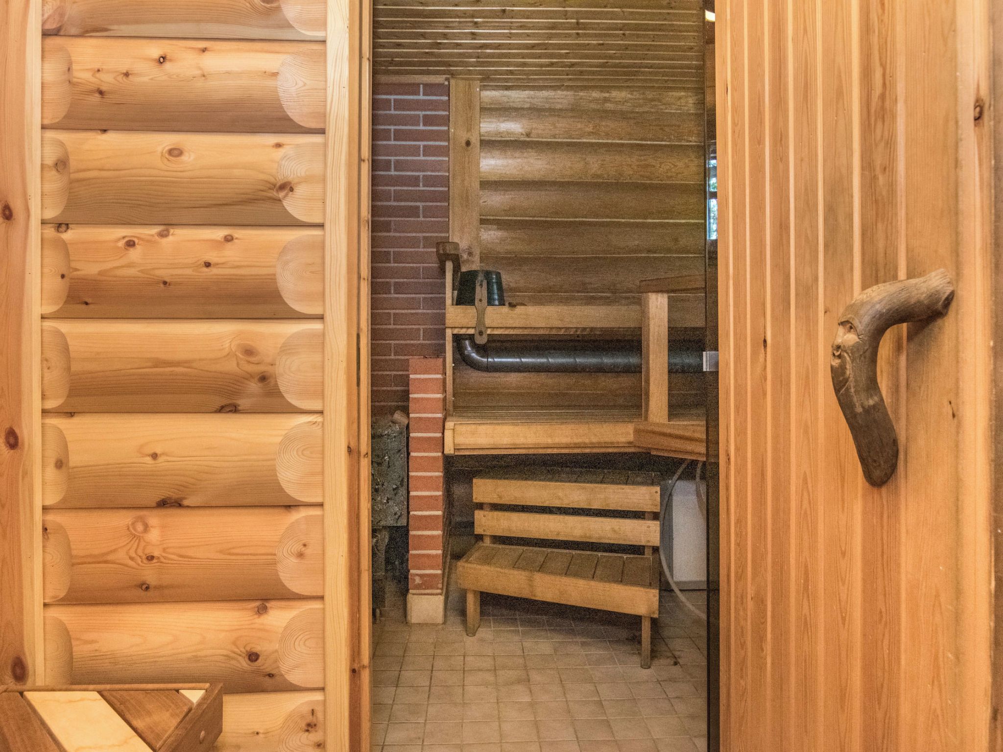 Een houten cabin met een open haard, een bakstenen muur en een houten bank.