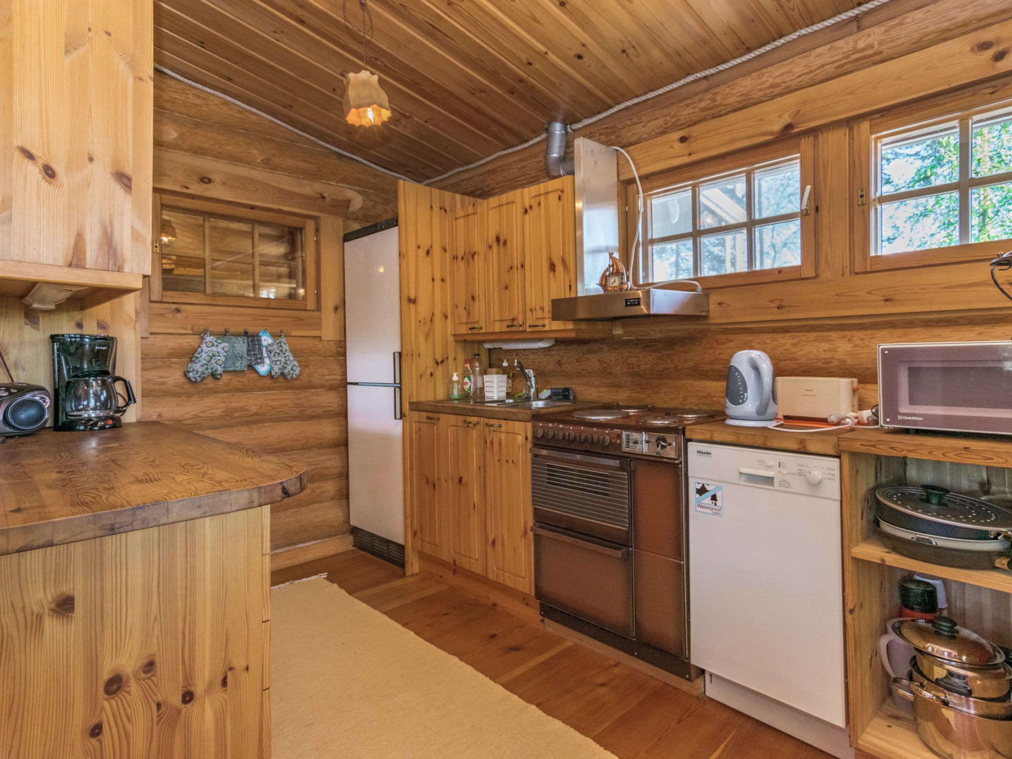 Una cocina estilo cabaña de madera con refrigerador, estufa, microondas y armarios de madera.