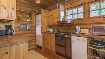 Una cocina estilo cabaña de madera con refrigerador, estufa, microondas y armarios de madera.