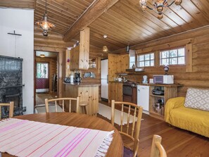 A cozy cabin interior with a dining area, kitchen, and a living room with a sofa.