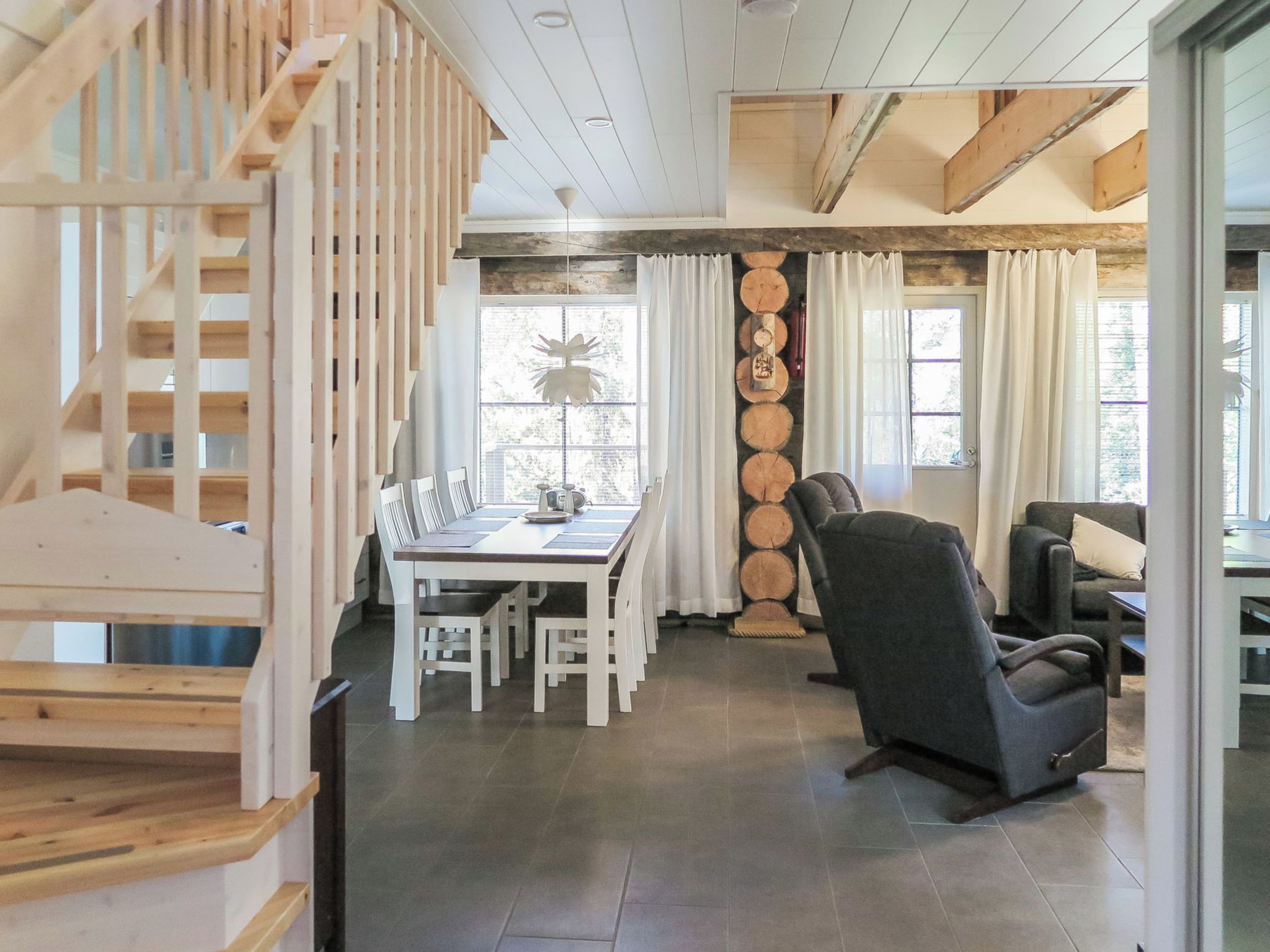 Un comedor con una escalera de madera, una mesa con sillas y una chimenea.