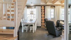 A spacious living area with a dining table, chairs, a sofa, and a staircase.