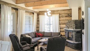 A cozy living room with a stone fireplace, a sectional sofa, and two armchairs.