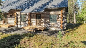 A log cabin with a metal roof, wooden deck, and a small porch.