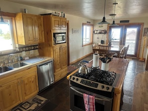 A kitchen with wooden cabinets, a dishwasher, a stove, and a dining area with a table and chairs.