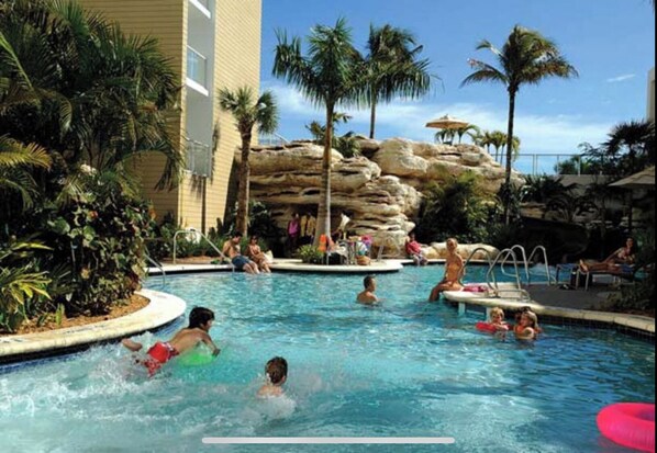 Relax by the pool surrounded by lush palm trees and tropical vegetation.