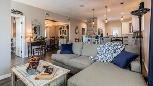 A spacious living room with a sofa, coffee table, and a dining area in the background. - Experience the Captain's Quarters.  A Historic 1920 American Four Square. (Tarpon Springs)