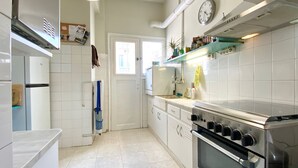 A kitchen with white cabinets, a stainless steel oven, and a window. - Sunny Apartment (90m2) in Athens center (Athens)
