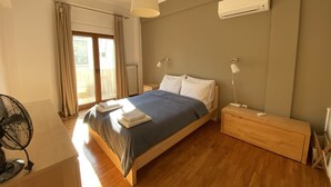 A bedroom with a bed, bedside lamps, an air conditioner, a fan, and a view through a sliding door. - Sunny Apartment (90m2) in Athens center (Athens)