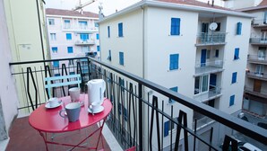 A balcony with a red table, white cups, and a white mug.