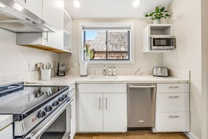 Une cuisine moderne avec des meubles blancs, un four encastré, un four à micro-ondes et un grille-pain.