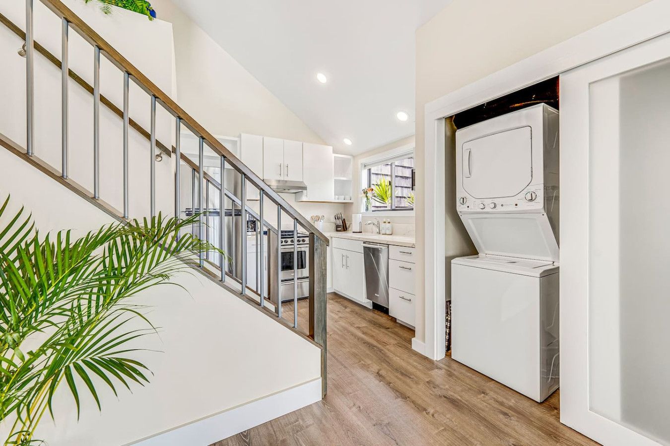 A modern kitchen with white cabinets, a stainless steel oven, and a built-in dishwasher.