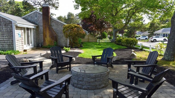 Un patio con sillas Adirondack y una chimenea de piedra.