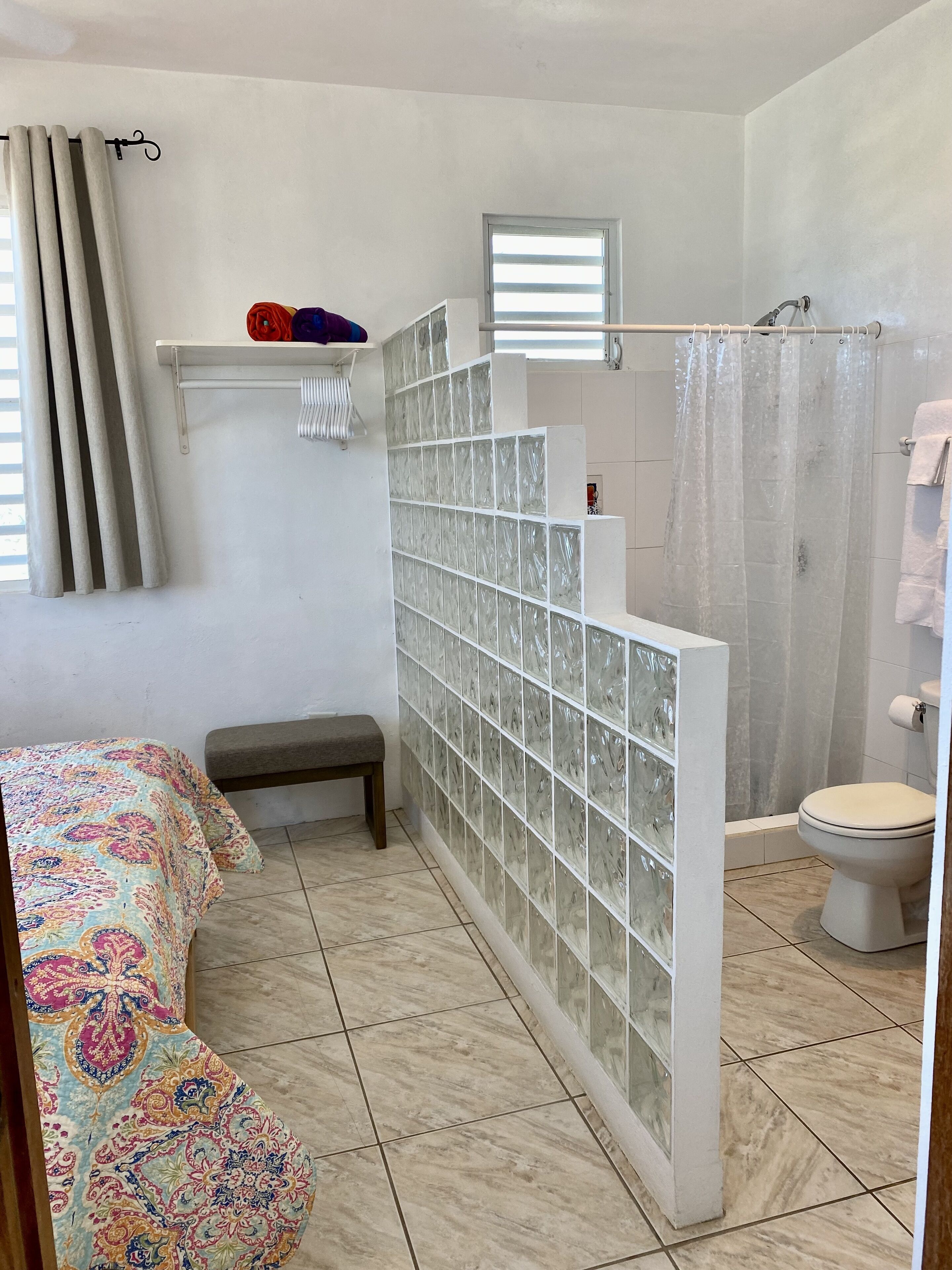 A bathroom with a shower, toilet, and bench.