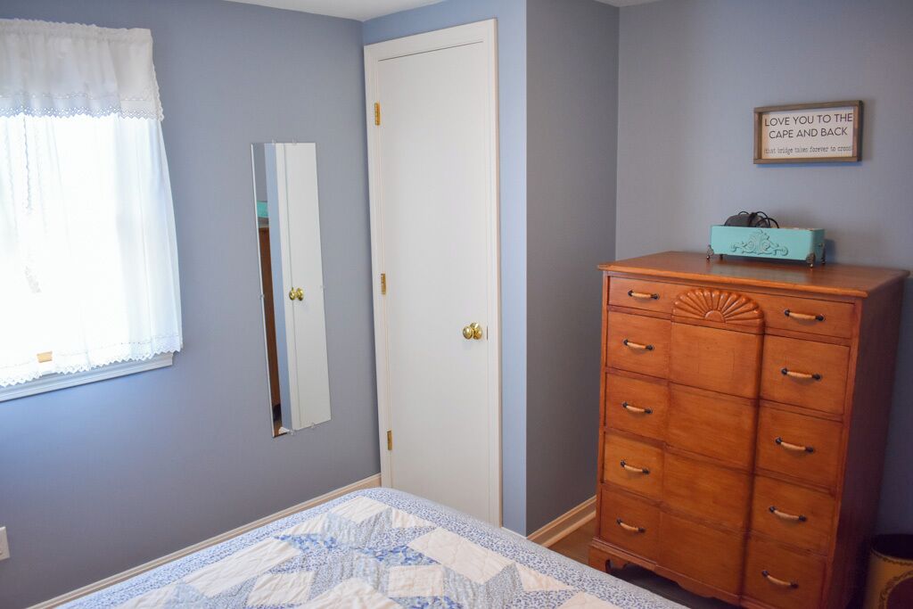 A bedroom with a bed, a dresser, a mirror, and a door.