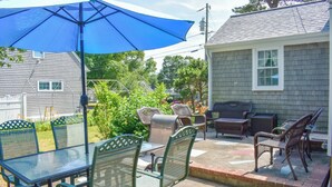 An outdoor patio with a table and chairs, a grill, and a blue umbrella. - Neat, clean and affordable 4 bedroom home with central air in West Dennis (West Dennis)