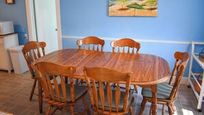A dining area with a wooden table and chairs, a painting on the wall, and a door. - Neat, clean and affordable 4 bedroom home with central air in West Dennis (West Dennis)