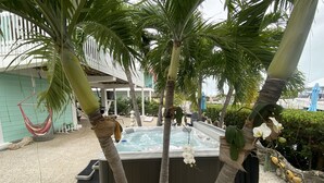 A hot tub surrounded by palm trees and a hammock.