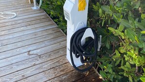 A white outdoor electrical box with a yellow switch on a wooden deck.