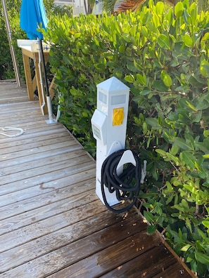 Una caja eléctrica exterior blanca con un interruptor amarillo sobre una terraza de madera.