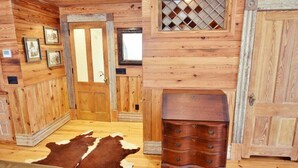 Un interior de madera con un tapete de cuero de vaca, un aparador de madera y cuadros en la pared.
