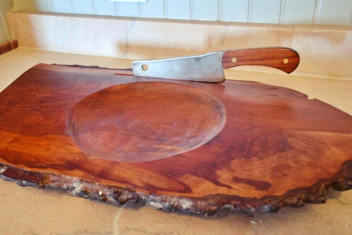 Una tabla de madera con un cuchillo sobre una encimera de cocina.