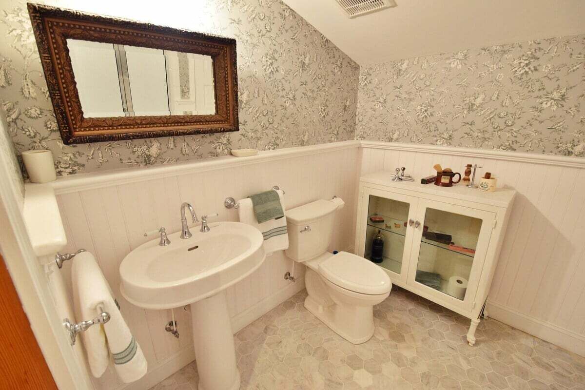 Une salle de bain avec un lavabo blanc, des toilettes et un meuble-lavabo doté de portes en verre.