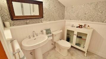 Une salle de bain avec un lavabo blanc, des toilettes et un meuble-lavabo doté de portes en verre.