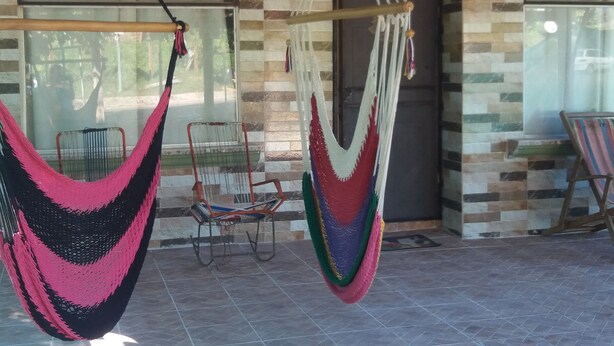 Une pièce avec deux hamacs, une chaise et un banc.