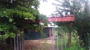 Un espace extérieur abrité, doté d’une clôture en métal, d’un toit rouge et de verdure.