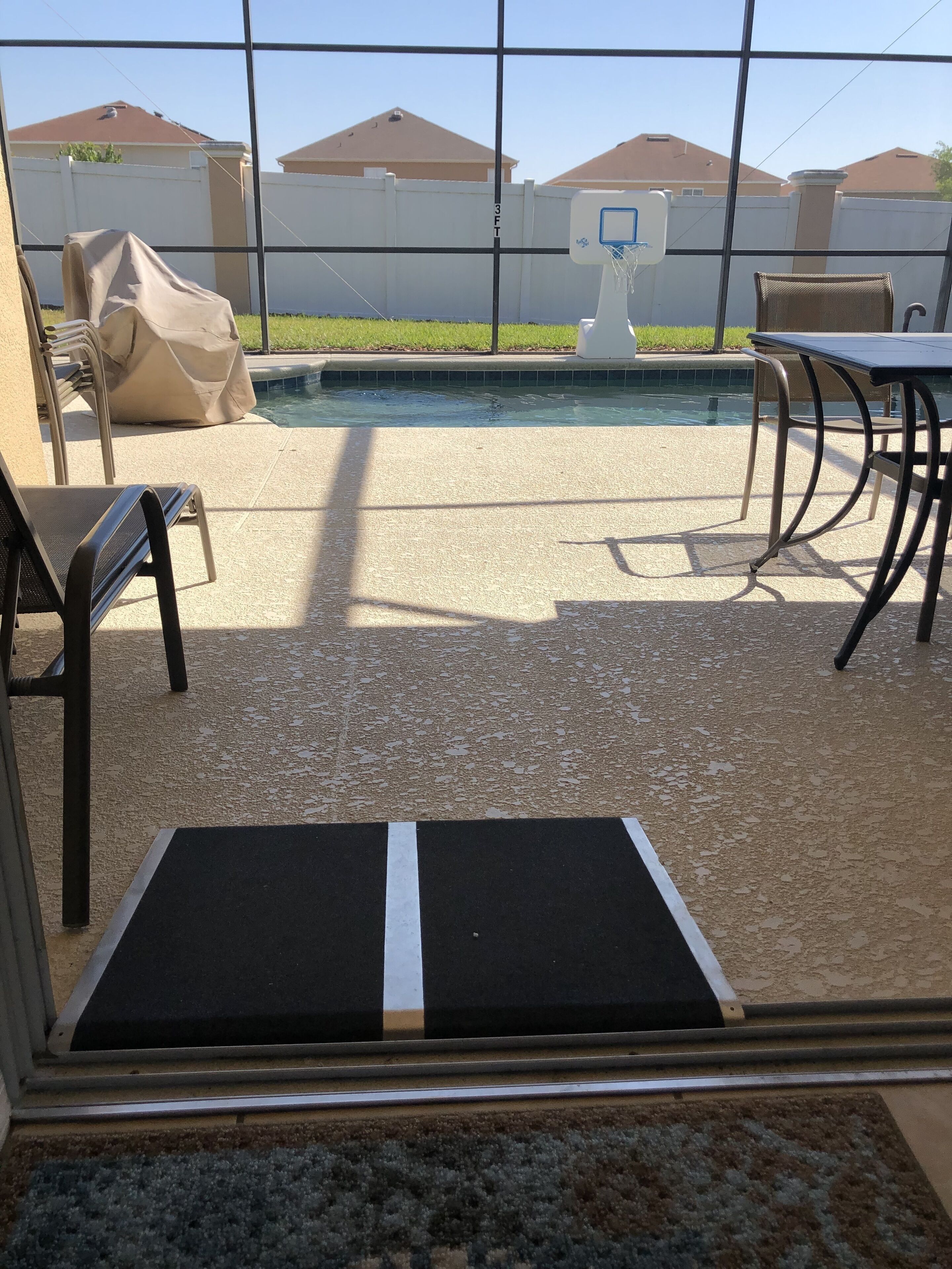 Un espace aménagé au bord de la piscine, comprenant un coin salon couvert, une piscine et un panier de basketball.