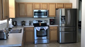 A modern kitchen with wooden cabinets, stainless steel appliances, a built-in oven, and a large refrigerator. - Disney great escape! Wheelchair accessible villa (Davenport)
