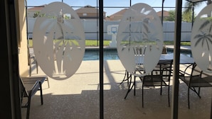 A covered outdoor seating area with tables and chairs, overlooking a swimming pool and a residential area. - Disney great escape! Wheelchair accessible villa (Davenport)