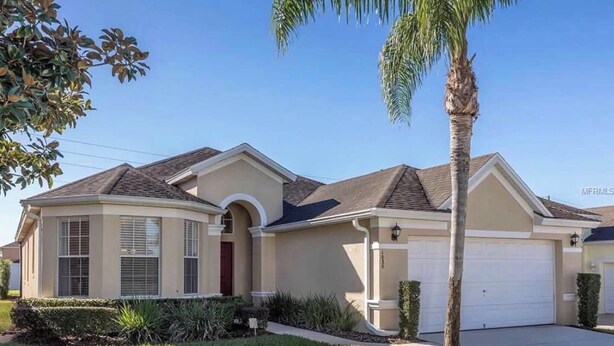 A single-story house with a beige exterior, a dark roof, and a white garage door. - Disney great escape! Wheelchair accessible villa (Davenport)
