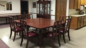 A dining area with a wooden table and chairs, a kitchen with wooden cabinets, and a ceiling fan. - Behnke's Country Center, Reedsville WI. EAA, Green Bay Packers, Road America (Reedsville)