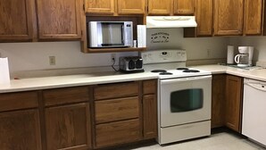 A kitchen with wooden cabinets, a microwave, a stove, and a coffee maker. - Behnke's Country Center, Reedsville WI. EAA, Green Bay Packers, Road America (Reedsville)