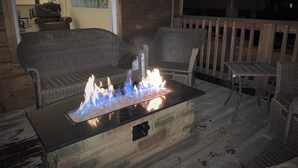 A cozy outdoor seating area with wicker furniture and a built-in fire feature.