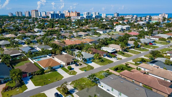 A residential area with houses, streets, and a distant city skyline. - NEW Pinball! Luxury Home, Stunning Large Pool/Spa, Close to Beaches, FREE Bikes (Naples)