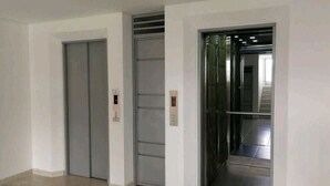 A hallway with two closed elevator doors and a visible elevator interior. - Aparta Suite Ventus (Tunja)