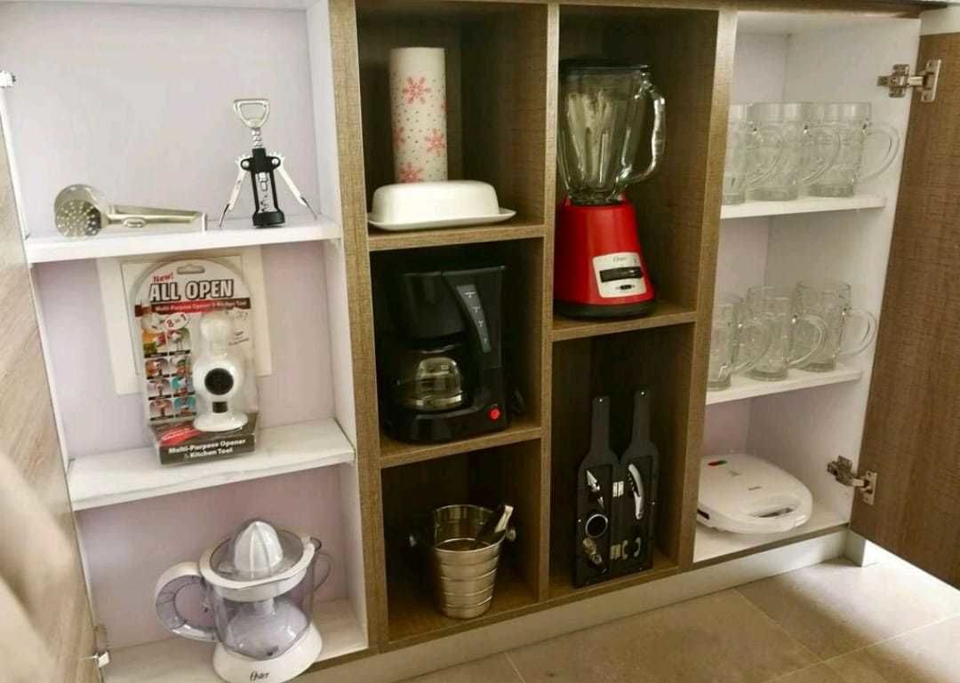 Una cocina con cafetera, licuadora, exprimidor y microondas.