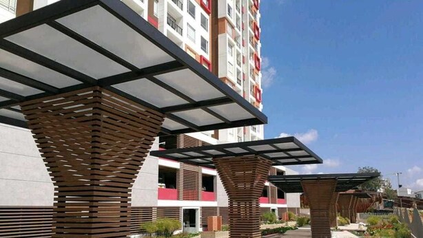 A modern outdoor area with wooden pergolas and a building in the background. - Aparta Suite Ventus (Tunja)