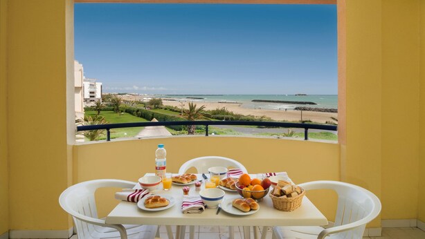 Ein Balkon mit Frühstückstisch und Blick auf den Strand.