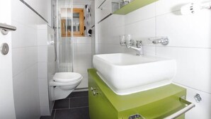 A modern bathroom with a white toilet, a green vanity, and a glass shower enclosure. - Bergfink Obergeschoss by Interhome (Grächen)