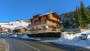 A multi-story wooden building with balconies, located in a snowy mountainous area. - Bergfink Obergeschoss by Interhome (Grächen)