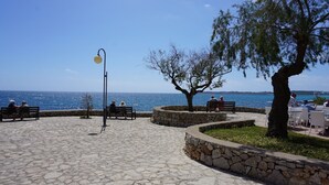 Un espacio al aire libre empedrado con bancos y un farol, con vista a una masa de agua.