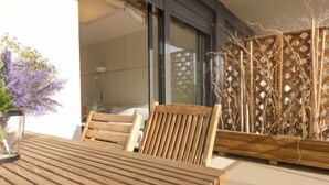 Un tavolo e sedie in legno su una terrazza esterna, con una porta in vetro e una struttura in legno traforata.