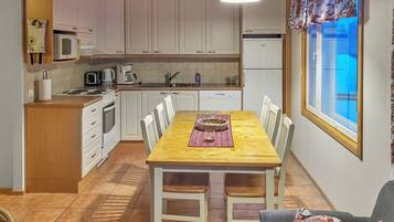 A compact kitchen with white cabinets, a dining table with chairs, and a window with a view.