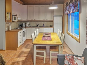 A compact kitchen with white cabinets, a dining table with chairs, and a window with a view. - Hilla 2 by Interhome (Äkäslompolo)