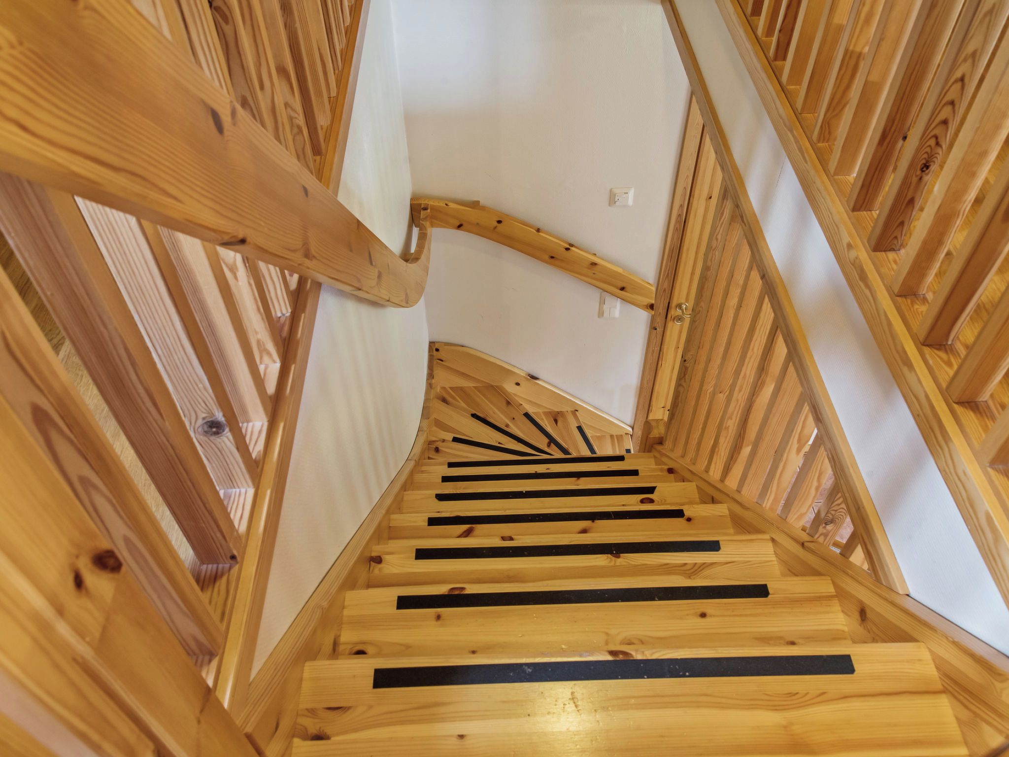 A wooden staircase with a handrail and a landing area.